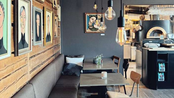 Eine Reihe von Tischen und Stühlen in einem Restaurant mit Bildern an der Wand