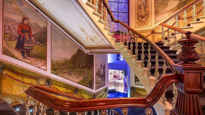 Eine Treppe in einem Gebäude mit Gemälden an den Wänden