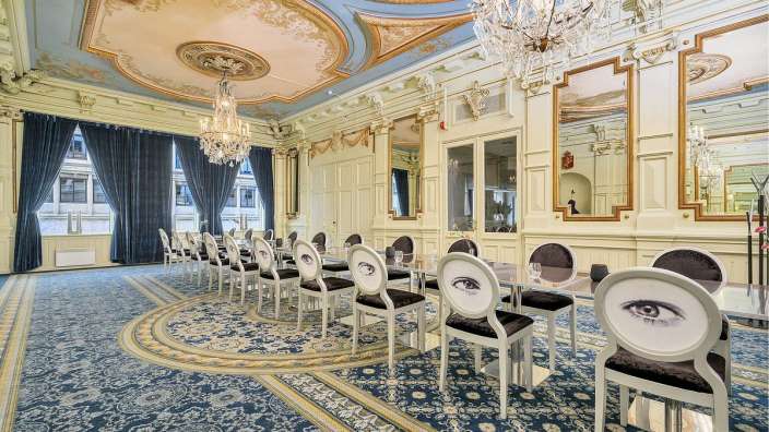 Ein Esszimmer mit vielen Stühlen und Tischen