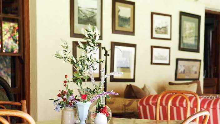 Ein Tisch mit Vasen mit Blumen darauf und Bildern an der Wand