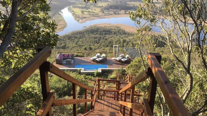 Eine Holztreppe führt hinunter zu einem Pool mit Blick auf einen Fluss