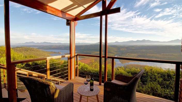 Ein Tisch mit zwei Gläsern Wein auf einem Deck mit Blick auf einen See
