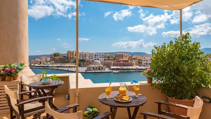 Ein Balkon mit einem Tisch und Stühlen mit Blick auf den Hafen