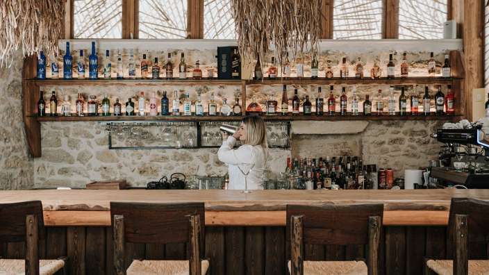 Eine Frau steht an einer Bar und schaut in ein Glas