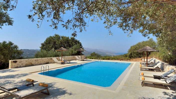 Liegestühle und Sonnenschirme umgeben einen großen Swimmingpool