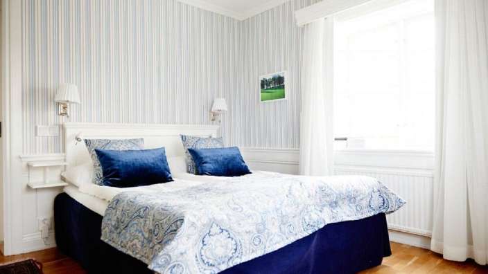 Ein Schlafzimmer mit blau-weiß gestreiften Wänden und einem Bett