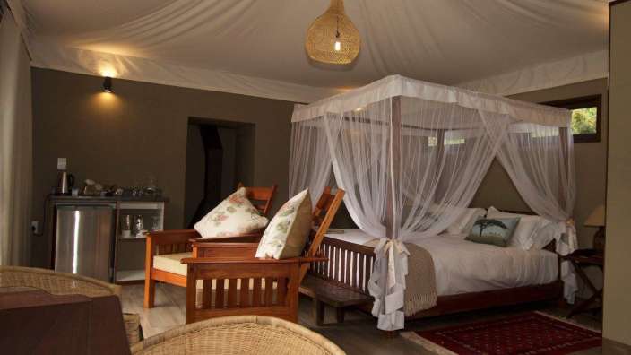 Ein Zimmer mit einem Himmelbett und einem Korbstuhl