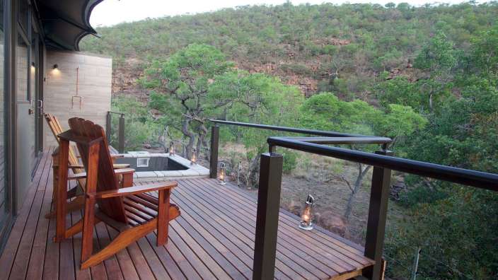 Zwei Holzstühle sitzen auf einem Holzdeck mit Blick auf den Wald