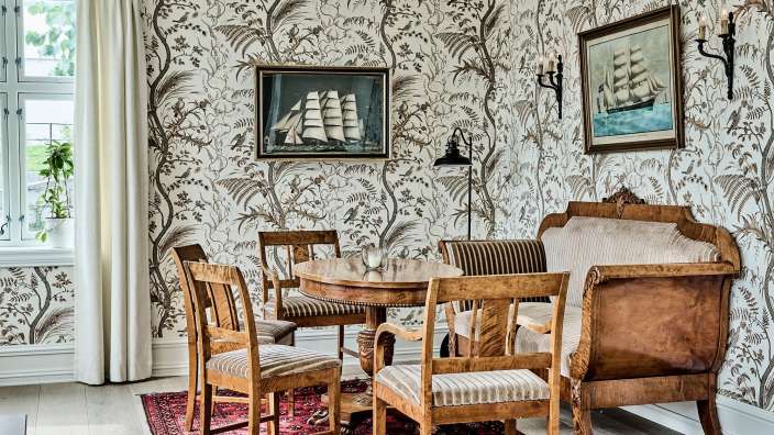 Ein Wohnzimmer mit einem Tisch und Stühlen und einem Gemälde eines Schiffes an der Wand