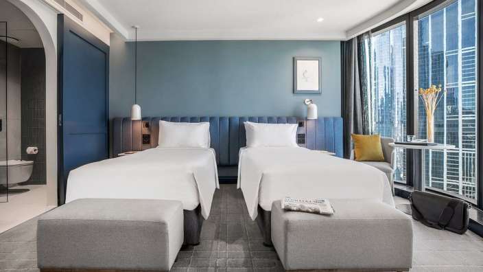 Ein Hotelzimmer mit zwei Einzelbetten und einem Zeitungsständer