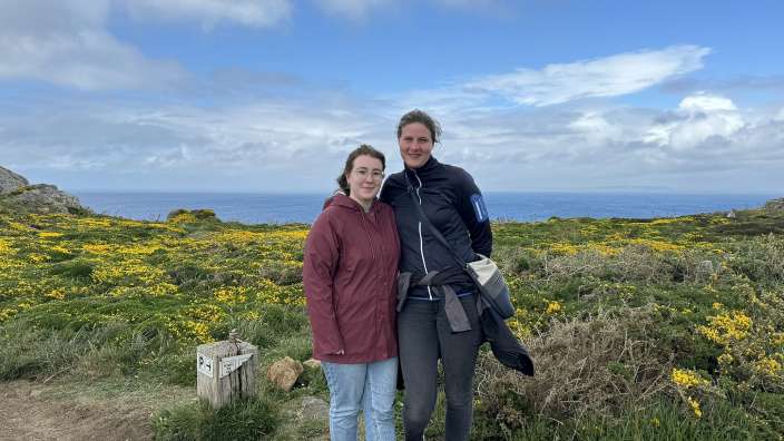 Zwei Frauen stehen nebeneinander in einem Feld mit gelben Blumen