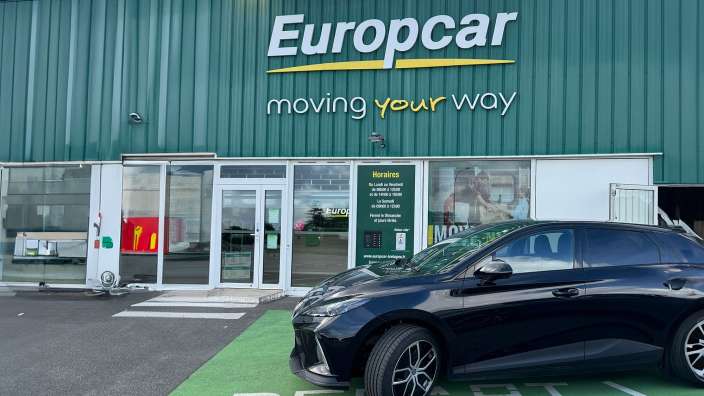 Ein schwarzes Auto steht vor einem europacar-Geschäft