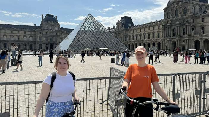 Zwei junge frauen stehen mit fahrrädern vor einer pyramide