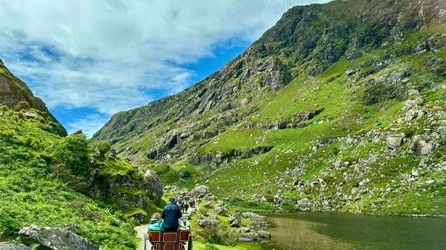 Eine Gruppe von Menschen fährt mit einem Pferdewagen eine Straße hinunter