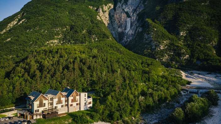 Ein Gebäude inmitten einer Bergkette mit einem Wasserfall dahinter