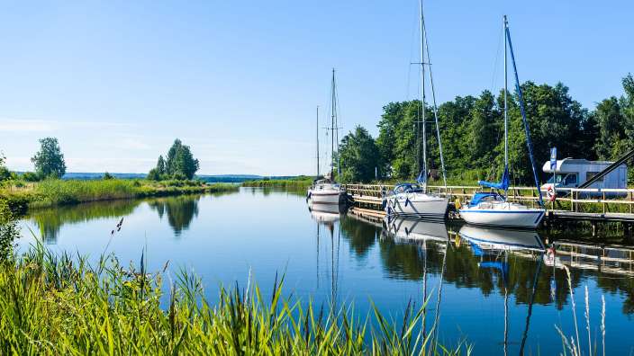 Eine Reihe von Booten, die an einem Dock an einem Fluss festgemacht sind
