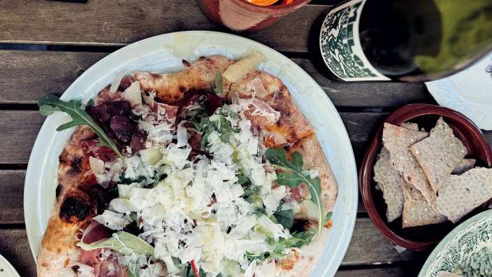 Ein weißer Teller mit einer Pizza und einer Flasche Wein darauf