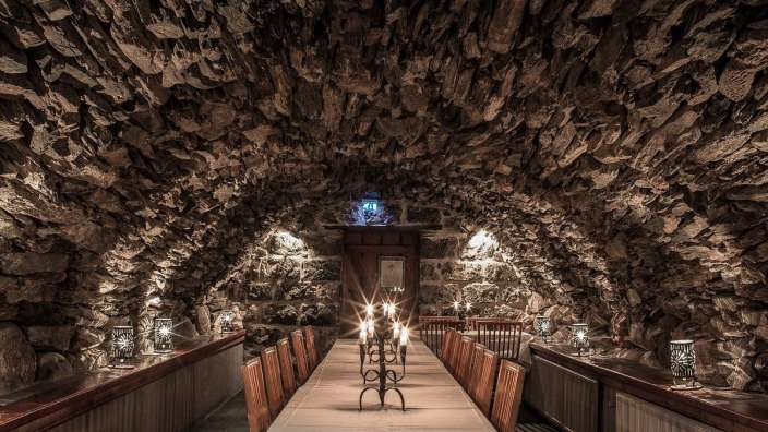 Ein langer Tisch mit Kerzen in einem Steinkeller