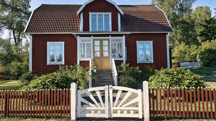 Ein rotes Haus mit weißen Fenstern und einem weißen Zaun