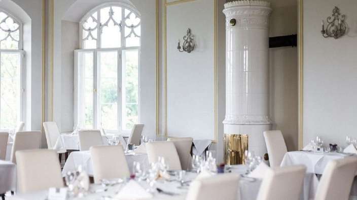 Ein Restaurant mit weißen Tischen und Stühlen und einem weißen Kamin