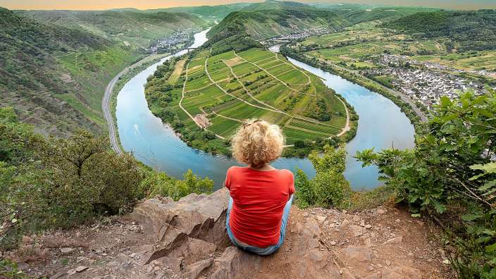Eine Frau sitzt auf einem Felsen mit Blick auf einen Fluss