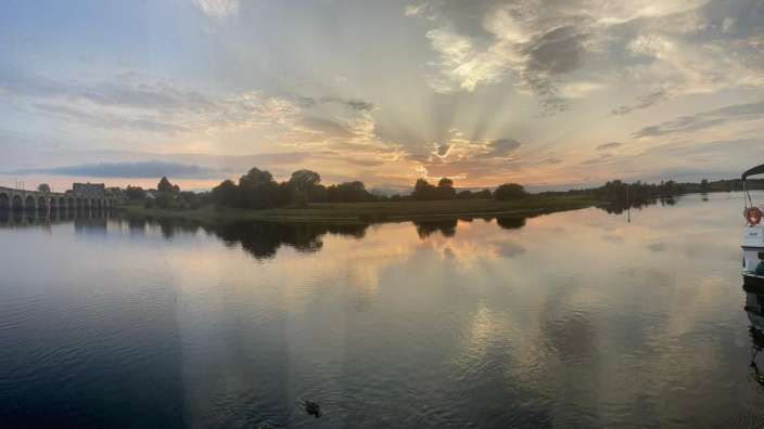Die Sonne scheint durch die Wolken über einem See