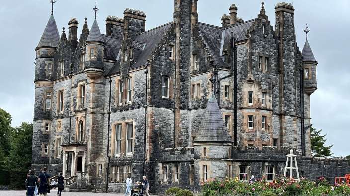 Eine Gruppe von Menschen steht vor einem großen Steingebäude