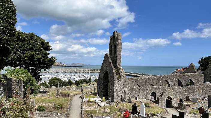 Ein Friedhof mit einer ruinierten Kirche im Hintergrund