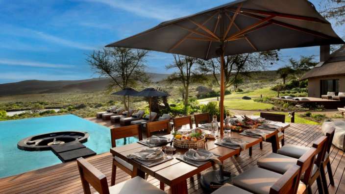 Ein Tisch und Stühle auf einer Terrasse mit Blick auf einen Pool
