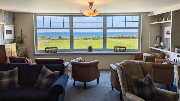Ein Wohnzimmer mit vielen Möbeln und einem großen Fenster mit Blick auf das Meer