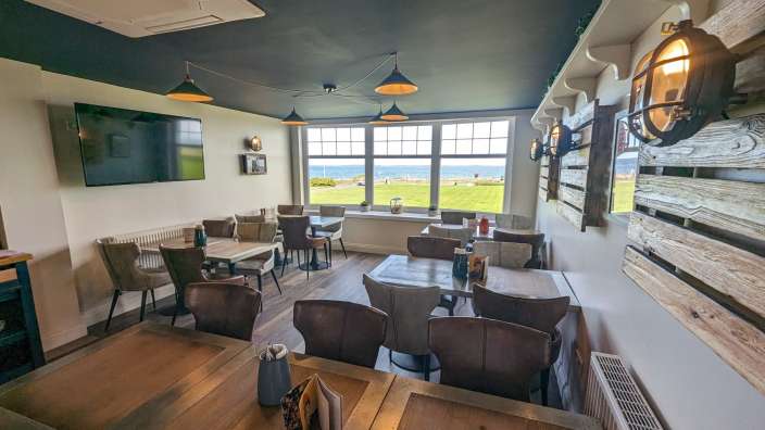 Ein Restaurant mit vielen Tischen und Stühlen und einem Fernseher