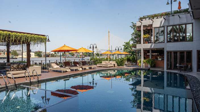 Ein großer Swimmingpool mit Liegestühlen und Sonnenschirmen umgeben