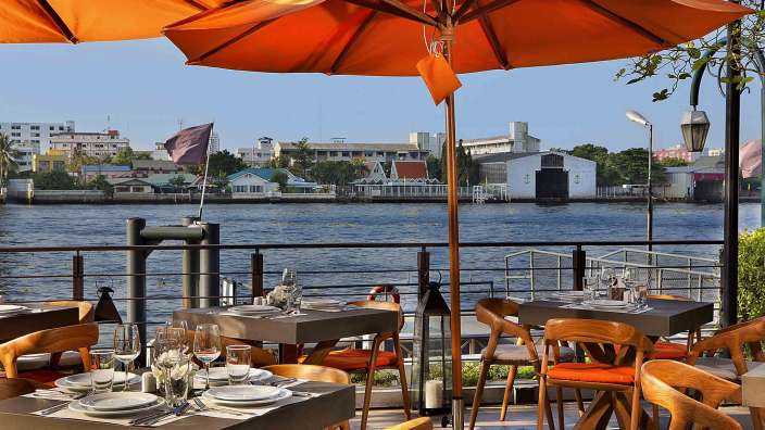 Tische und Stühle in einem Restaurant mit Blick auf den Fluss
