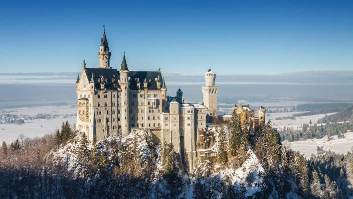Ein großes Schloss sitzt auf einem schneebedeckten Hügel