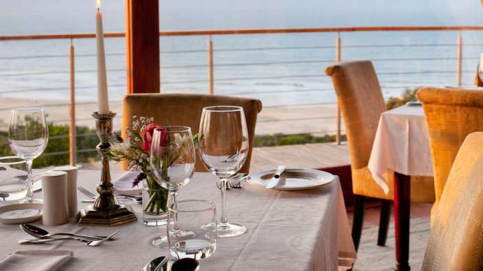Ein Tisch mit Gläsern und Kerzen auf einem Balkon mit Blick auf den Ozean