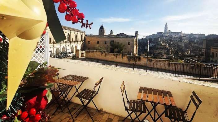 Ein Tisch und Stühle auf einem Balkon mit einem Gebäude im Hintergrund