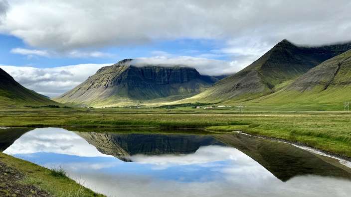 Ein Berg spiegelt sich im Wasser eines Sees