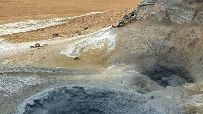 Menschen stehen neben einem großen Loch in der Wüste