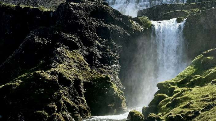 Ein Wasserfall in den Bergen mit einem Fluss darunter