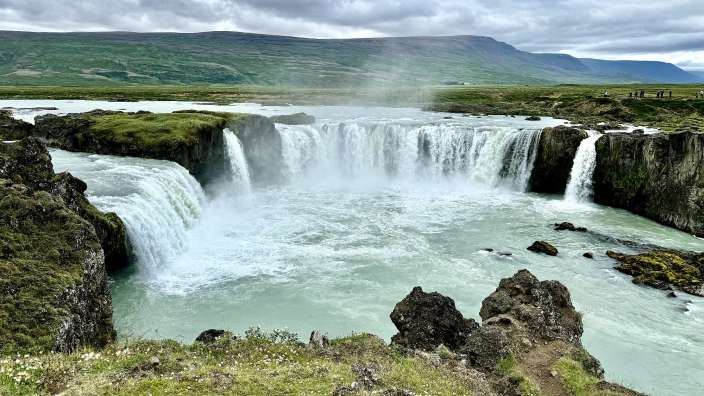 Ein Wasserfall mit einem Berg im Hintergrund