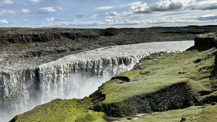 Eine Gruppe von Menschen steht an der Seite eines Wasserfalls