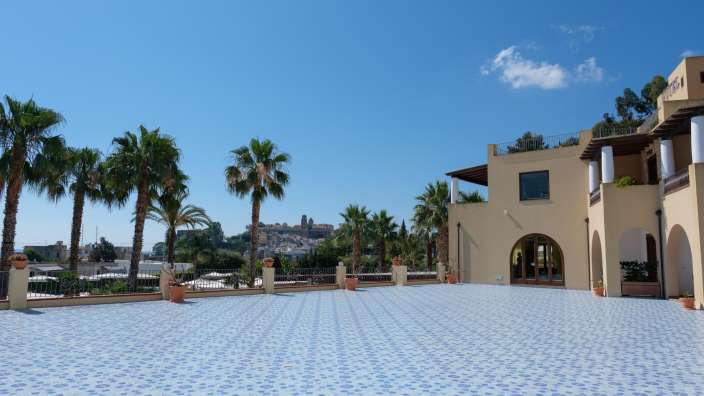 Ein großes Gebäude mit Palmen und einem blau-weißen Fliesenboden