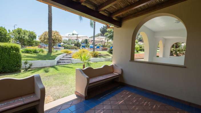 Eine Bank auf einer Veranda mit Blick auf einen Garten