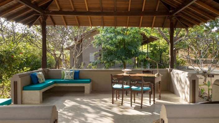 Eine Terrasse mit einem Tisch und Stühlen unter einem Holzdach