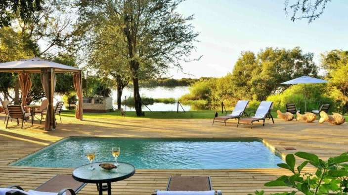 Ein Holzdeck mit einem Swimmingpool und Liegestühlen
