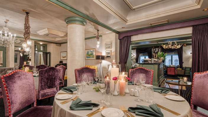 Ein Esszimmer mit einem runden Tisch und lila Stühlen