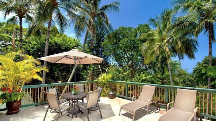 Eine Terrasse mit einem Tisch und Stühlen und einem Regenschirm