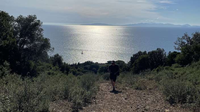 Ein Mann läuft auf einem Feldweg zum Meer
