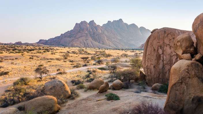 Eine Wüste mit großen Felsen und Bergen im Hintergrund