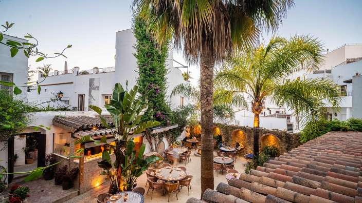 Eine Terrasse mit Tisch und Stühlen und Palmen